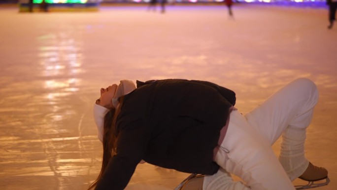 跟踪拍摄自信的年轻女子在冰鞋上以慢动作弯腰站起来。现场摄像机跟随快乐放松的高加索溜冰者在城市的夜晚享