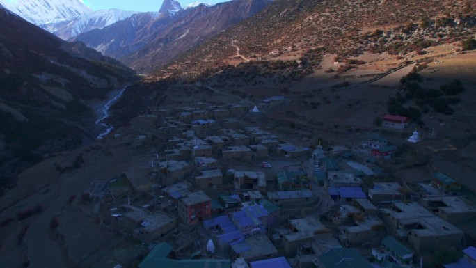 从空中倾斜的角度看，五颜六色的尼泊尔传统康沙尔村房屋在马南区。喜马拉雅山脉落日背景下的提里科大本营步