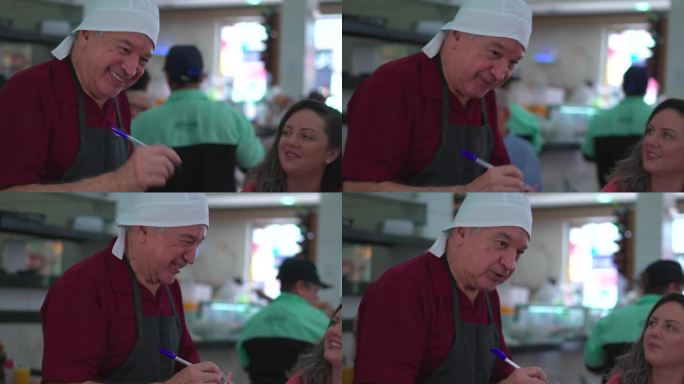 在传统的自助餐厅里，一位资深的巴西服务员正在为顾客点菜。快乐的人在与人互动的同时在记事本上写下食物订