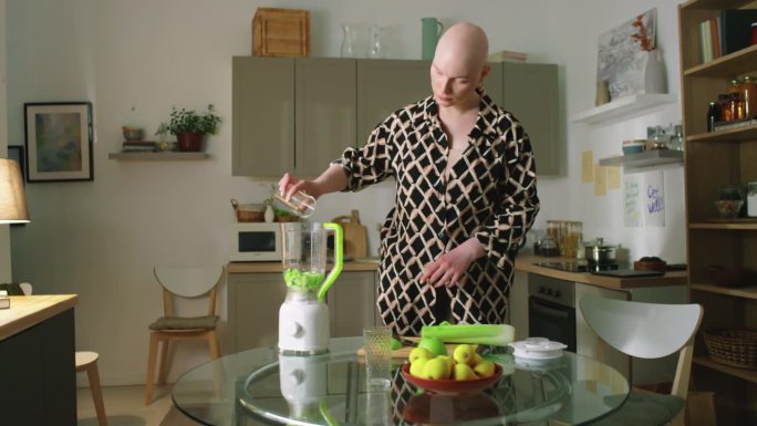 一个秃顶女人把水加到苹果搅拌机里做冰沙