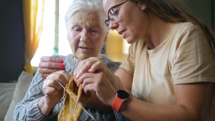 80年代的老妇人教专注的孙女如何用毛线编织。