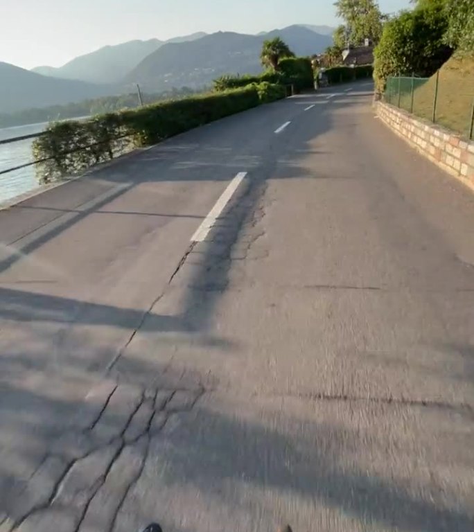 POV骑公路自行车在日落沿着湖路