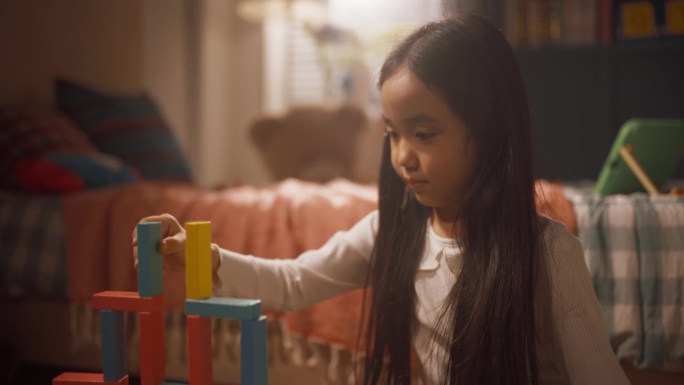 小女孩在儿童房聚精会神玩积木的肖像。快乐的韩国女孩创造性地花时间，梦想成为一名建筑师