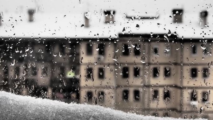 窗外的景色到冬天解冻了。融化的雪堆和雨滴落在玻璃上。多层建筑，有很多窗户。忧郁和泪水还是春天的到来。