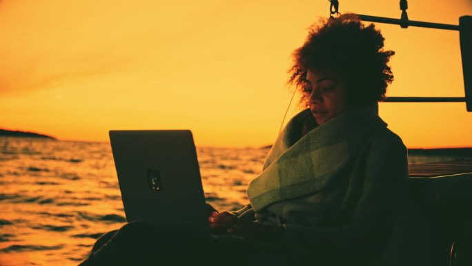 年轻女子在帆船上使用笔记本电脑