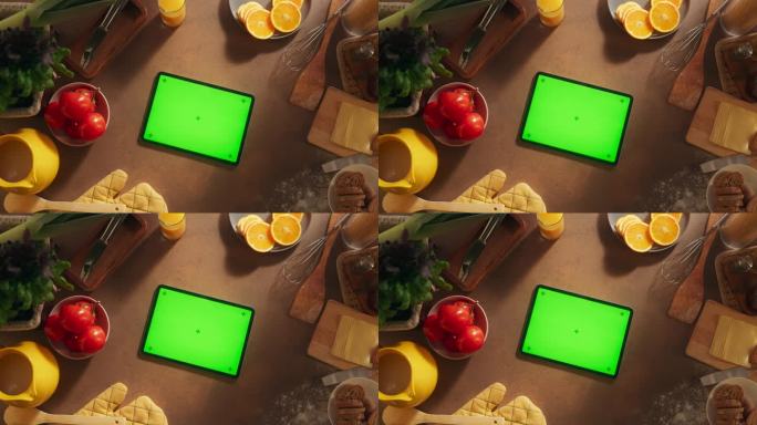 一个平板电脑与模拟绿色屏幕显示的自上而下的视图。一个设备水平躺在木制厨房桌子上的静态镜头。在线教程和