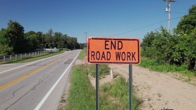 结束道路工程，在农村道路和田地旁边有黑色文字的橙色标志