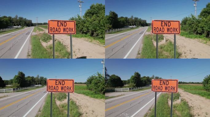 结束道路工程，在农村道路和田地旁边有黑色文字的橙色标志