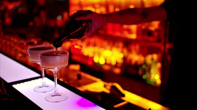 夜晚的酒吧里，酒保用白起泡酒调制鸡尾酒，红色的霓虹灯，慢动作
