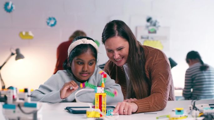 孩子、学生和老师在机器人课堂上进行教育、学习和发展。一名妇女和一名小女孩一起在教室里用平板电脑进行编