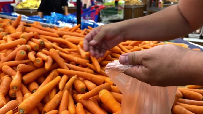 用手把胡萝卜分门别类放进塑料袋里，在商店里买水果