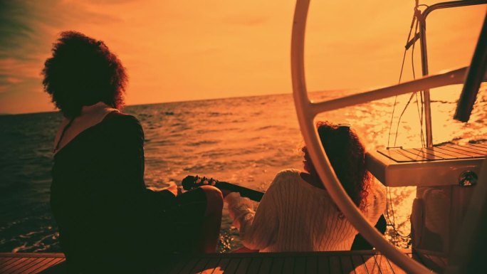 一名女子在帆船甲板上欣赏她的女友弹吉他