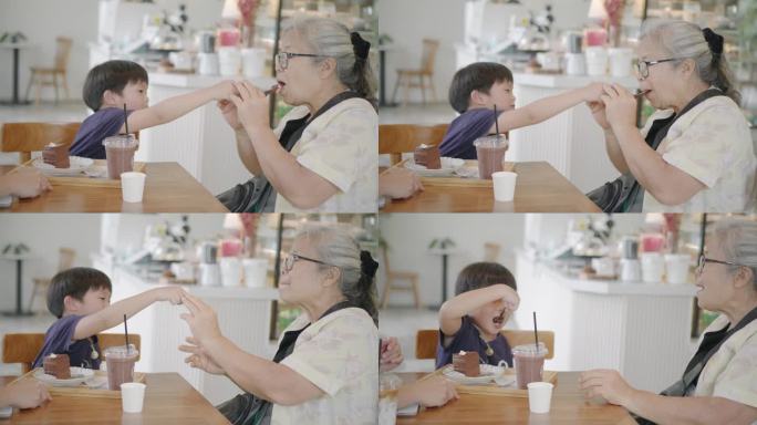 一位亚洲祖母和她的孙子正在蛋糕店一起吃巧克力蛋糕。