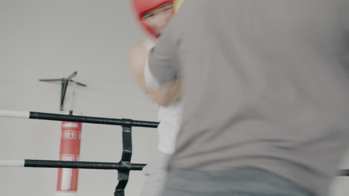 两名男子拳击搭档戴着手套和头盔在健身房训练