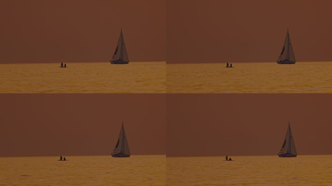 剪影游客在日落时在海洋中划桨