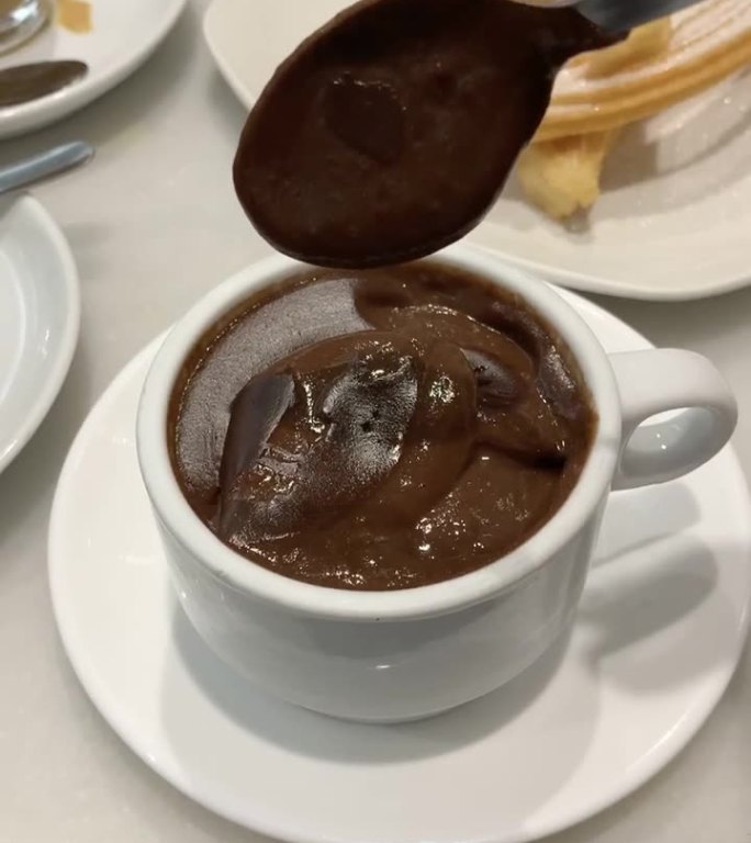 巧克力布丁正在用勺子搅拌，背景是糖油条
