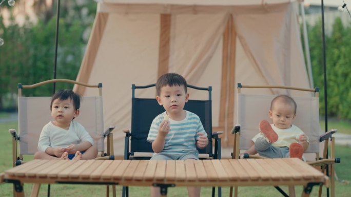 年轻的冒险:亚洲男孩和他的兄弟在户外吃零食，拥抱大自然的美丽
