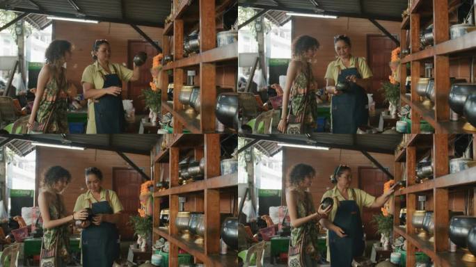 一位对僧侣产品感兴趣的快乐妇女向曼谷一家手工艺品店的老板询问价格。