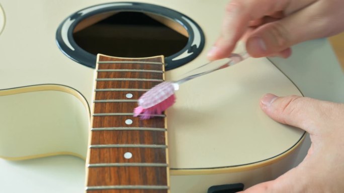 男子用喷雾清洗白色原声吉他。吉他服务理念。4k视频片段UHD 3840x2160