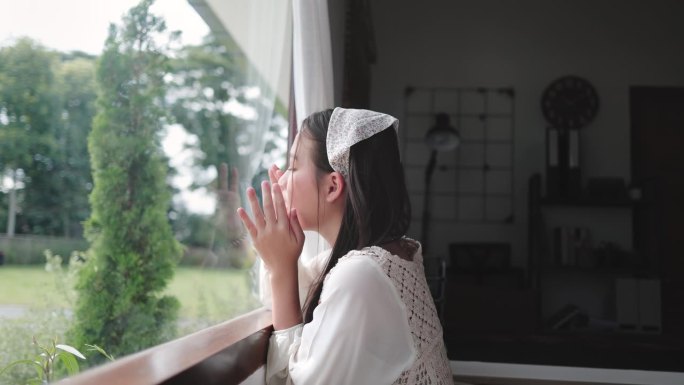 孤独的亚洲女孩在窗边无聊