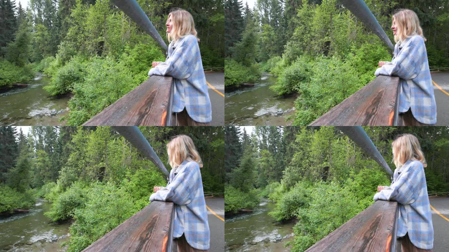 年轻女子欣赏着蜿蜒穿过森林的小溪