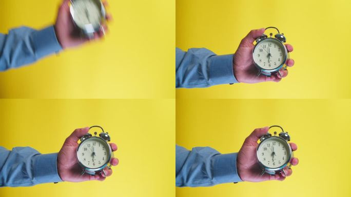 一个男人的手拿着一个黄色背景的闹钟，一个男人在一个孤立的背景上显示时间6点钟。