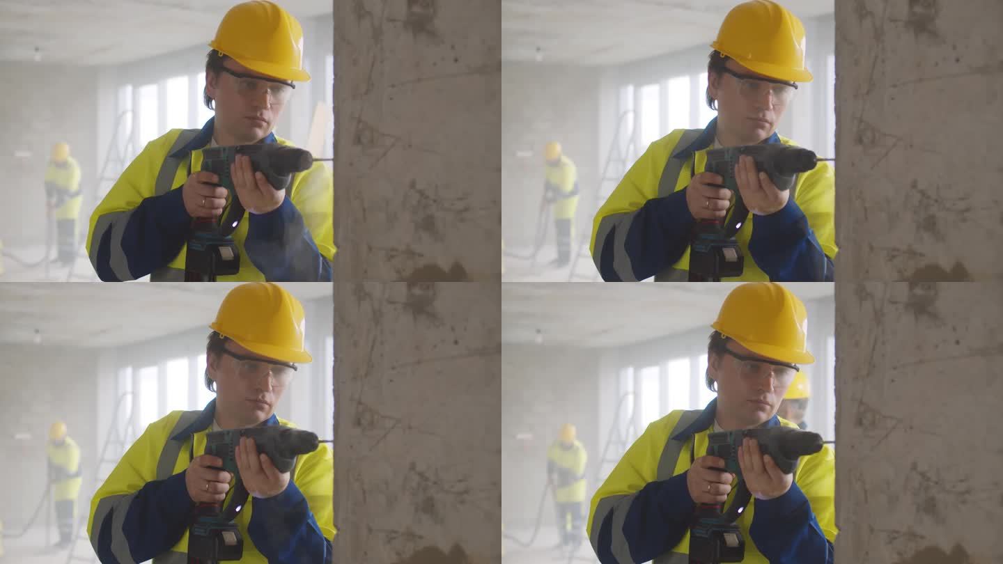 工人戴着头盔和眼镜，用电钻在墙上打洞