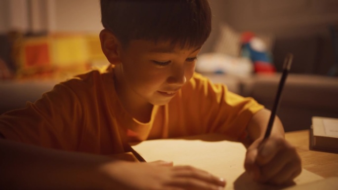 一个可爱的韩国小男孩晚上在客厅的笔记本上思考和写作的跟踪肖像。聪明的孩子给他最好的朋友写信，询问消息