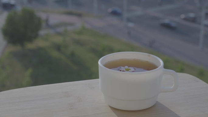 阳台桌上的白瓷杯热甘菊茶