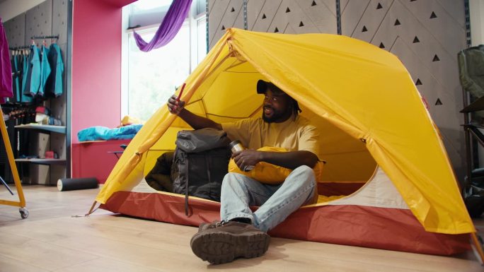 想象的逃离:快乐的非裔美国人露营模拟室内露营冒险在一个黄色的帐篷