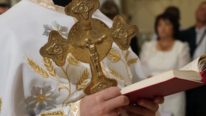 在教堂做礼拜时，牧师手里拿着十字架在看书。