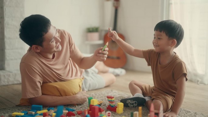 珍惜团聚:亚洲父子在家玩玩具的爱与笑。