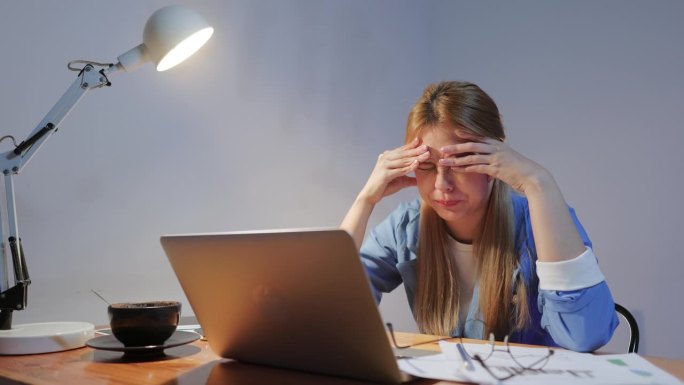 工作过度疲劳的年轻亚洲女性，在电脑工作后感到头痛，办公室综合症和伸展。压力大的成年女商人