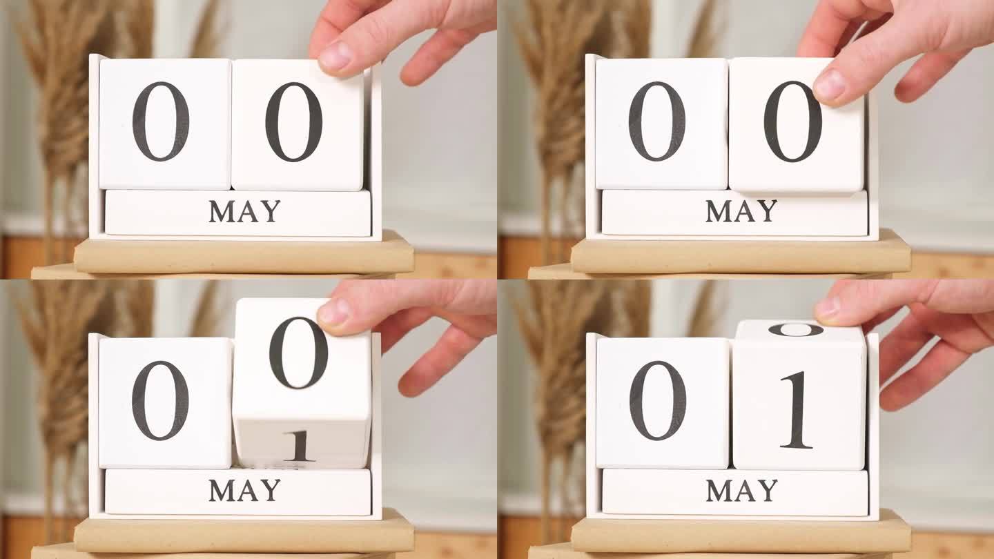这个人把日期写在日历上5月1日。5月1日。桌上放着五一木制日历。春季的一天