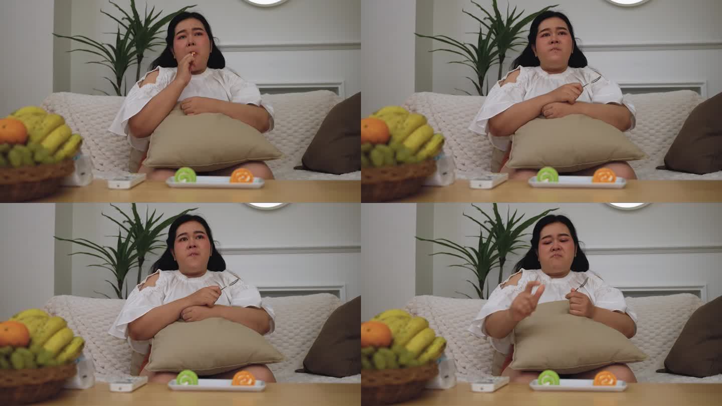 亚洲肥胖女性一边看电视剧，一边吃，不健康的生活理念。