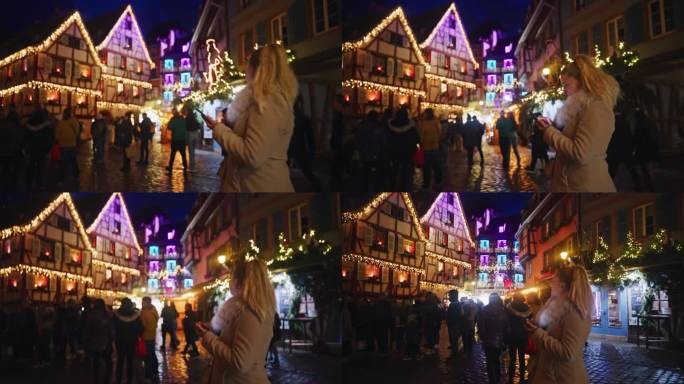 在科尔马一个热闹的圣诞市场上，一名女子边走边玩她的智能手机