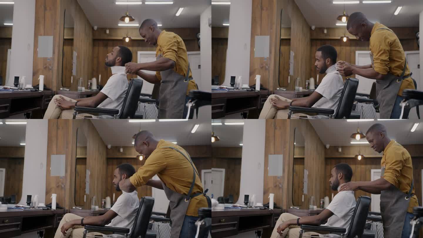 一个非洲裔美国人在理发店里坐在镜子前的椅子上准备理发