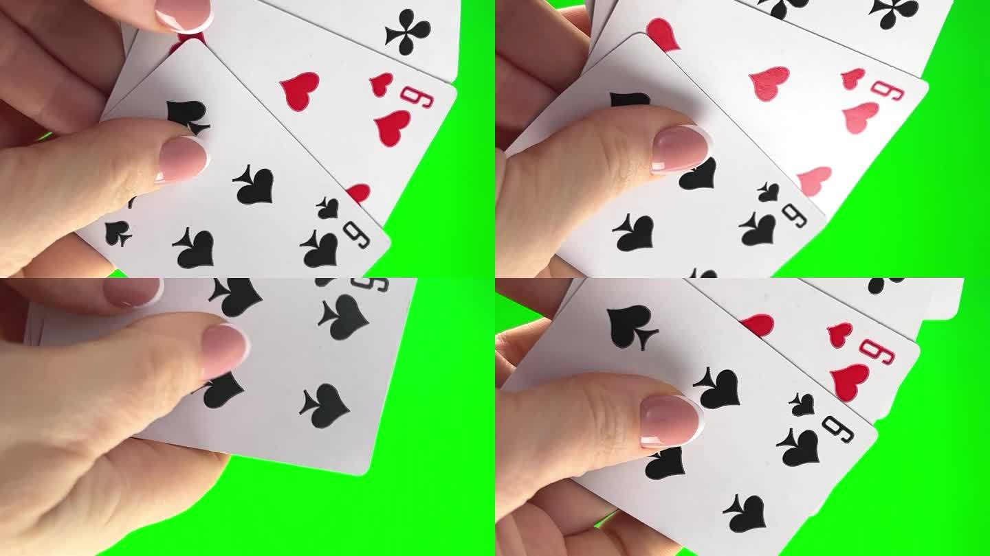 手拿着绿色背景上的四个六，特写女性的手和法国美甲女把卡片分类放在一起，像扇子一样展开。同花色剩下四张