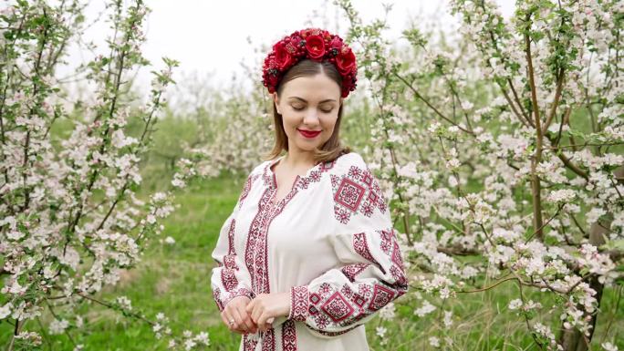 美丽的乌克兰女人在花园里的肖像。女孩身穿传统刺绣服装，头戴红色花环。乌克兰自由，春天，民族服饰，战争