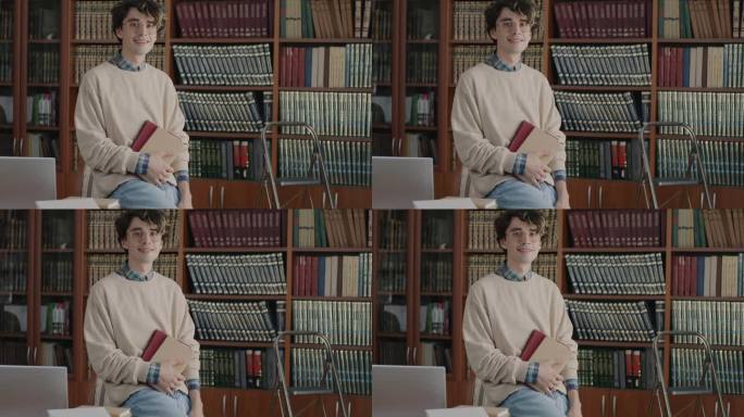 在大学图书馆里，一个聪明的年轻学生拿着书，带着淡淡的微笑看着镜头的慢动作肖像