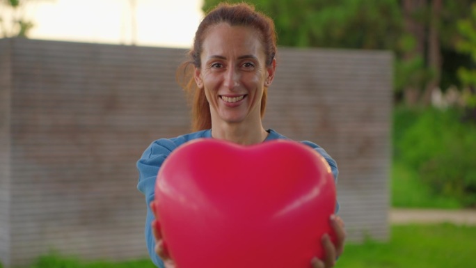 一个手里拿着红心气球的快乐女人的肖像。情绪积极的女孩调情。情人节