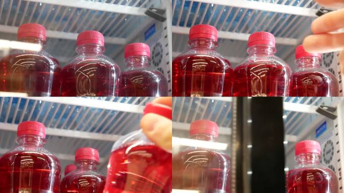冰箱里装着粉红色苏打水的塑料瓶的特写，一只男性的手打开门，拿了一个