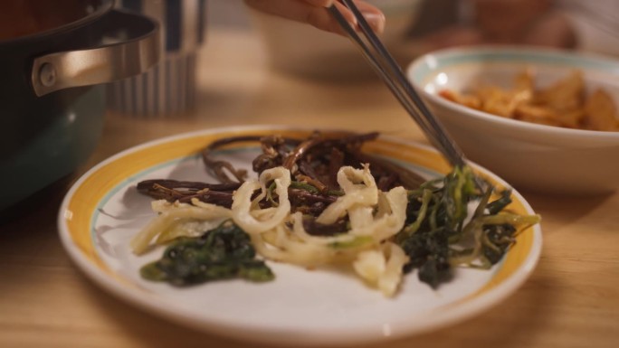 韩国素食配菜特写:匿名人士用金属筷子夹熟蔬菜沙拉。餐桌上的亚洲素食。健康的传统亚洲食品