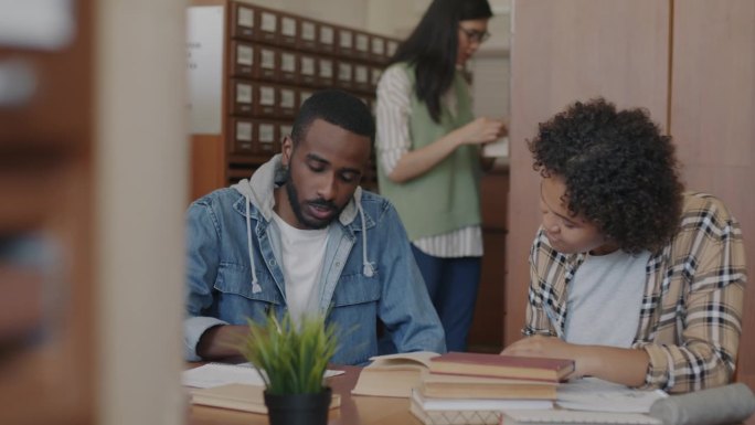 非裔美国学生男女一起在大学图书馆写作、阅读、讨论书籍、学习