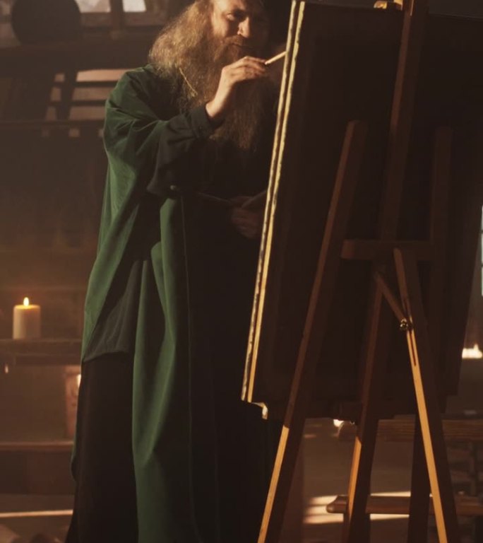 竖屏:文艺复兴时期的老男性艺术家在他的古董工作室的画布上作画。才华横溢的历史人物在他的杰作上工作，在