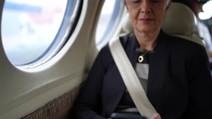 一位高级女商人在公司飞机上使用手机的肖像