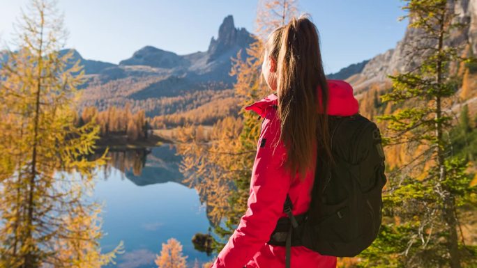 秋天，一位女冒险家正在欣赏山间湖泊的壮丽景色