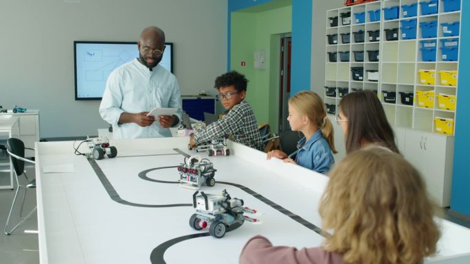 年轻的多民族儿童在科技俱乐部玩电动机器人