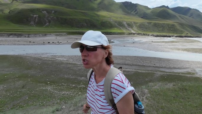 一位兴高采烈的女游客正在用视频记录她在Saryjaz河谷的旅行。自拍的观点