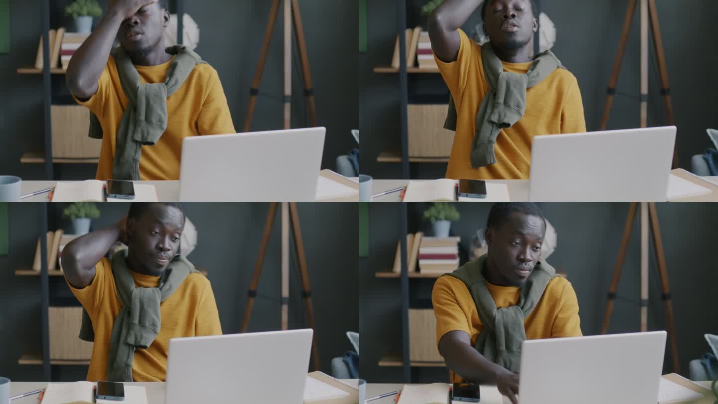 疲惫的年轻非裔美国人在家里用笔记本电脑触摸脸，感到压力